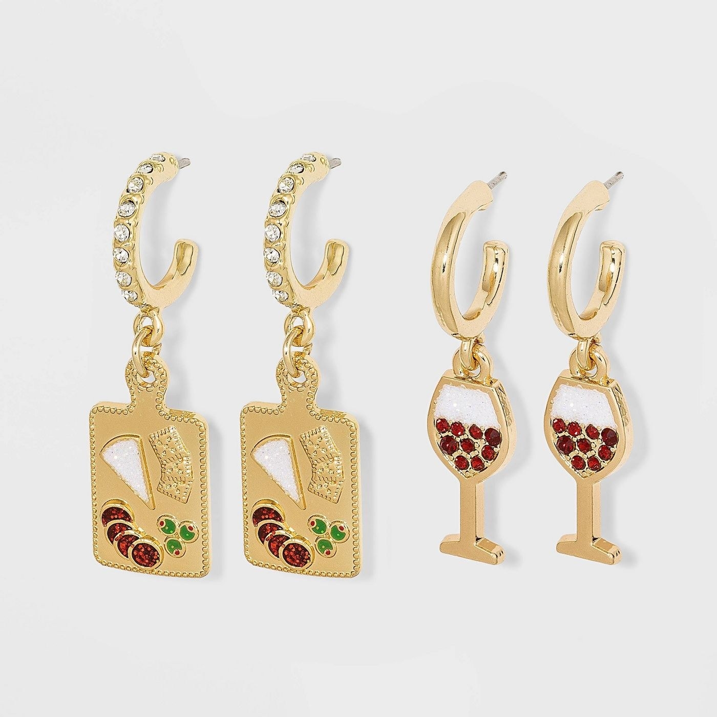two pairs of gold huggie hoops with charms that look like a cheese board and wine glasses, respectively