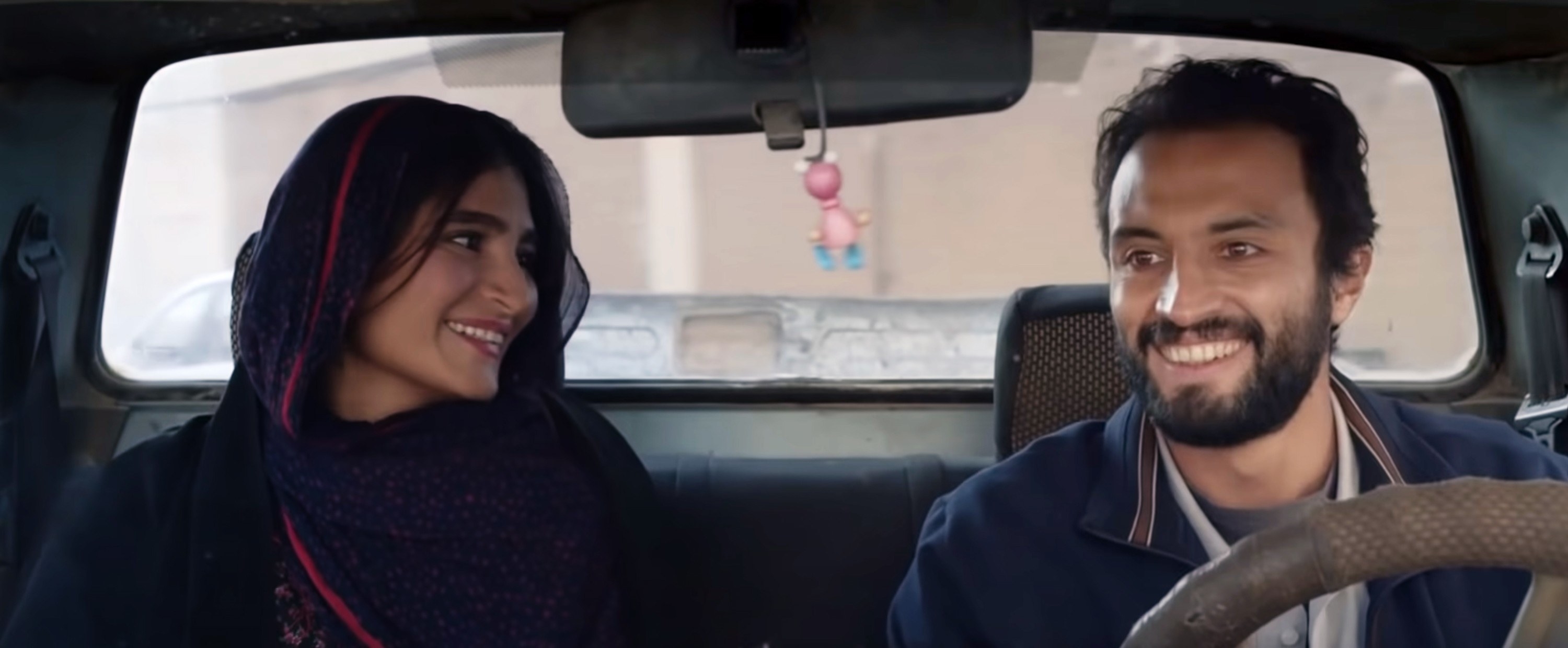 Sahar Goldust and Amir Jadidi smile in a car