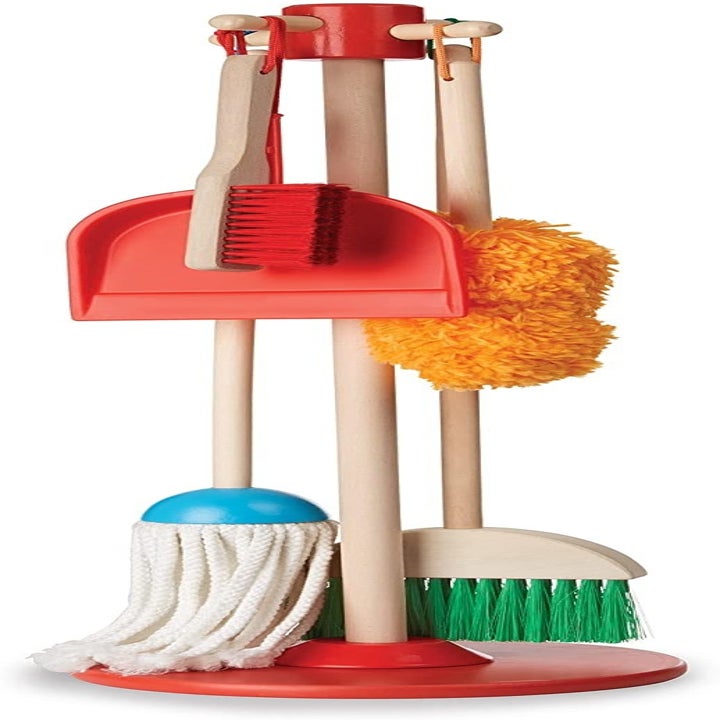 A broom, mop, duster, brush, and dustpan handing on the wooden organizing stand