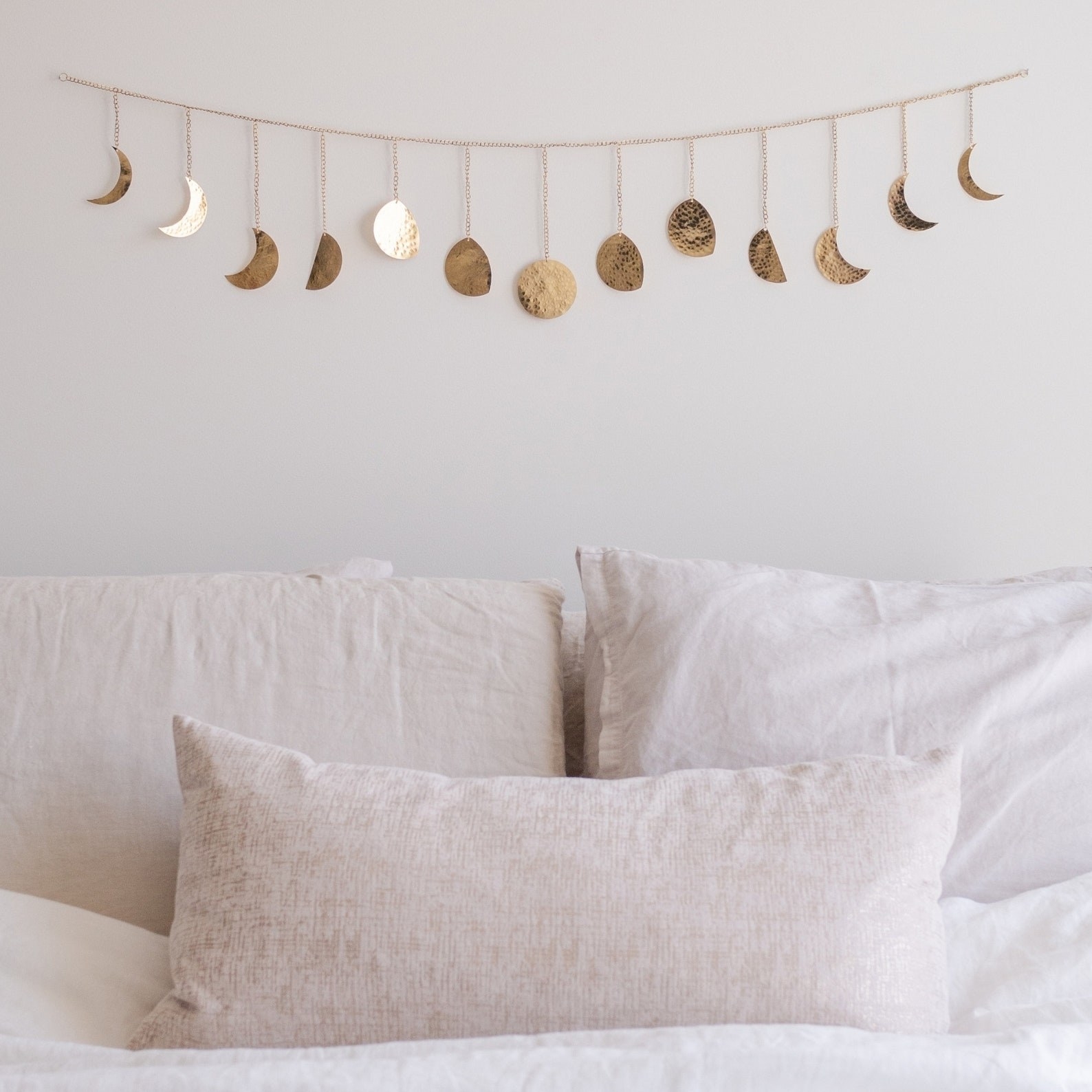 the gold moon phase garland hung above a bed