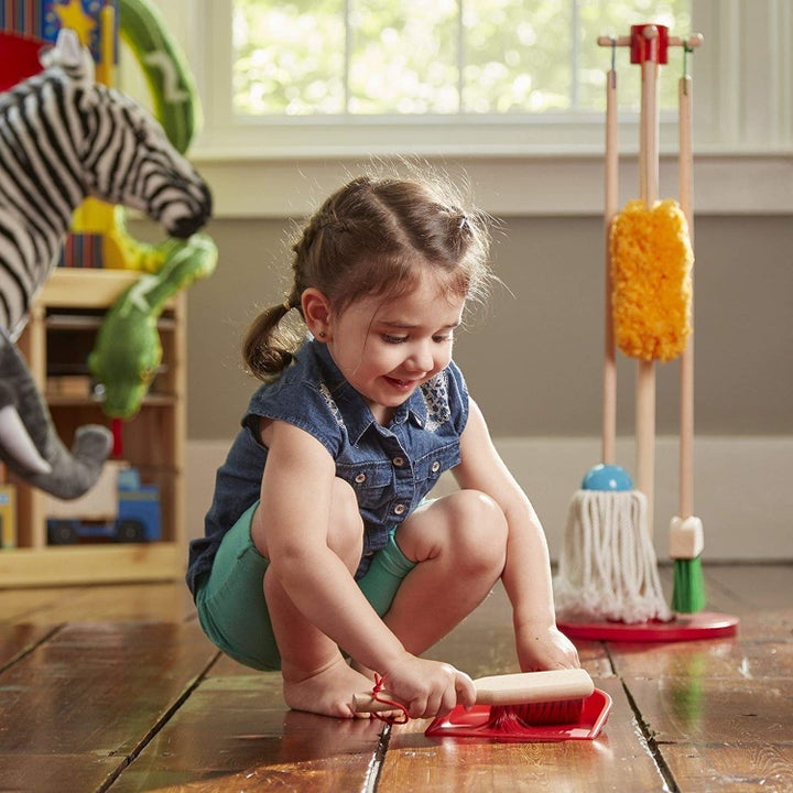 A child cleaning the floor with the duster and dustpan