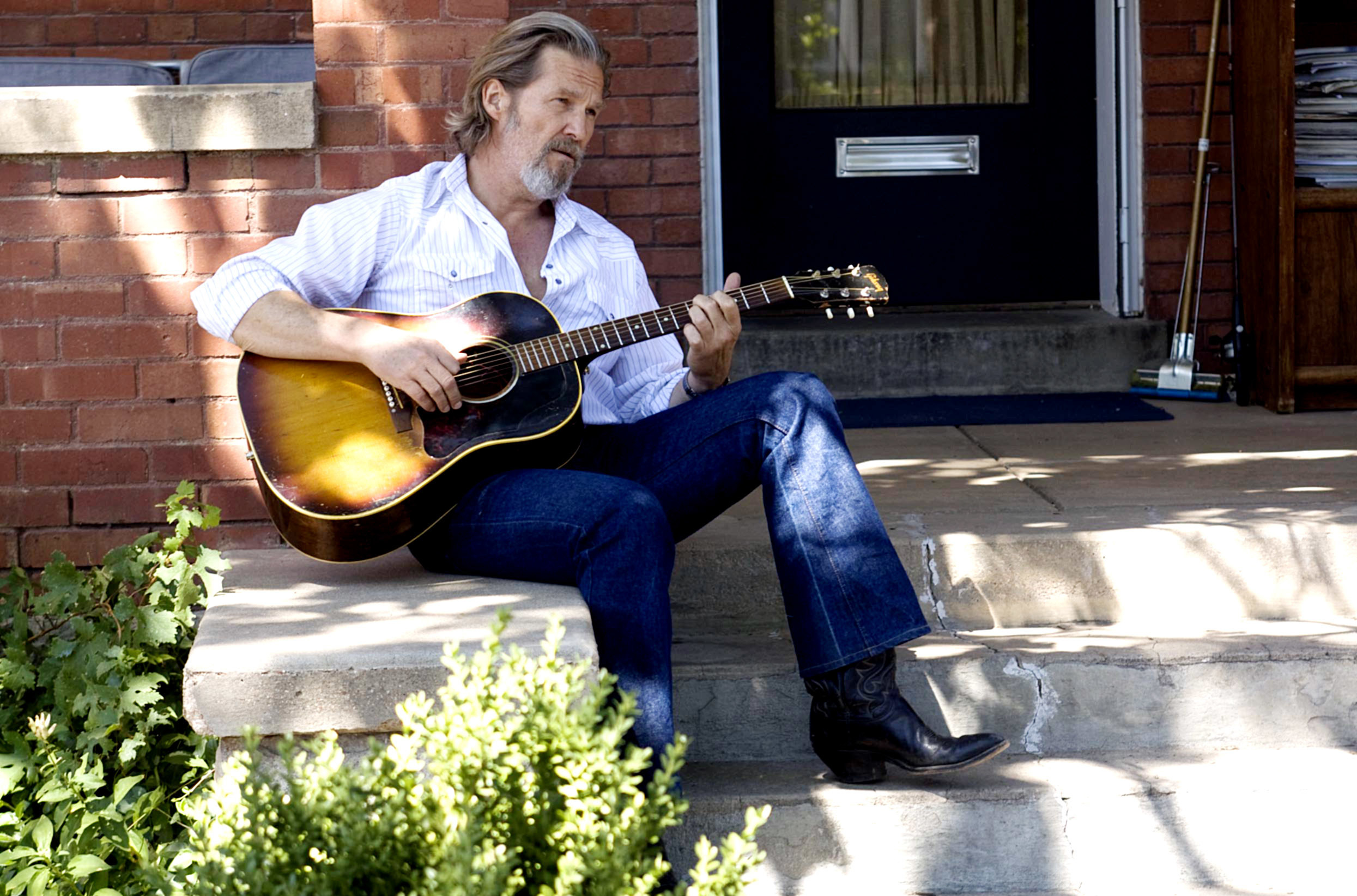 Jeff Bridges plays the guitar on a stoop