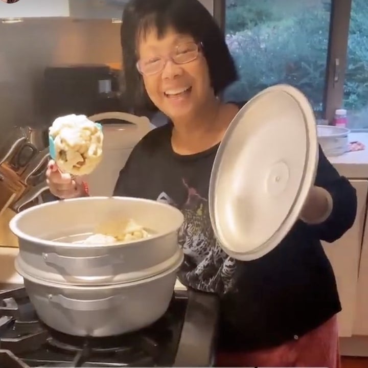 Olivia's mom smiles while holding open a pot to show off her cooking