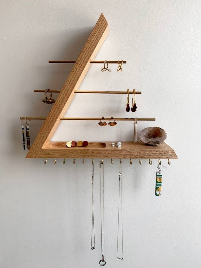 the oak and gold brass jewelry holder filled with earrings, rings, and necklaces