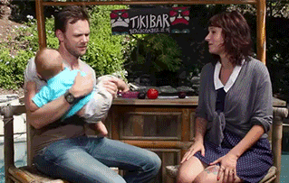 Joel Mchale handing off a baby to a woman