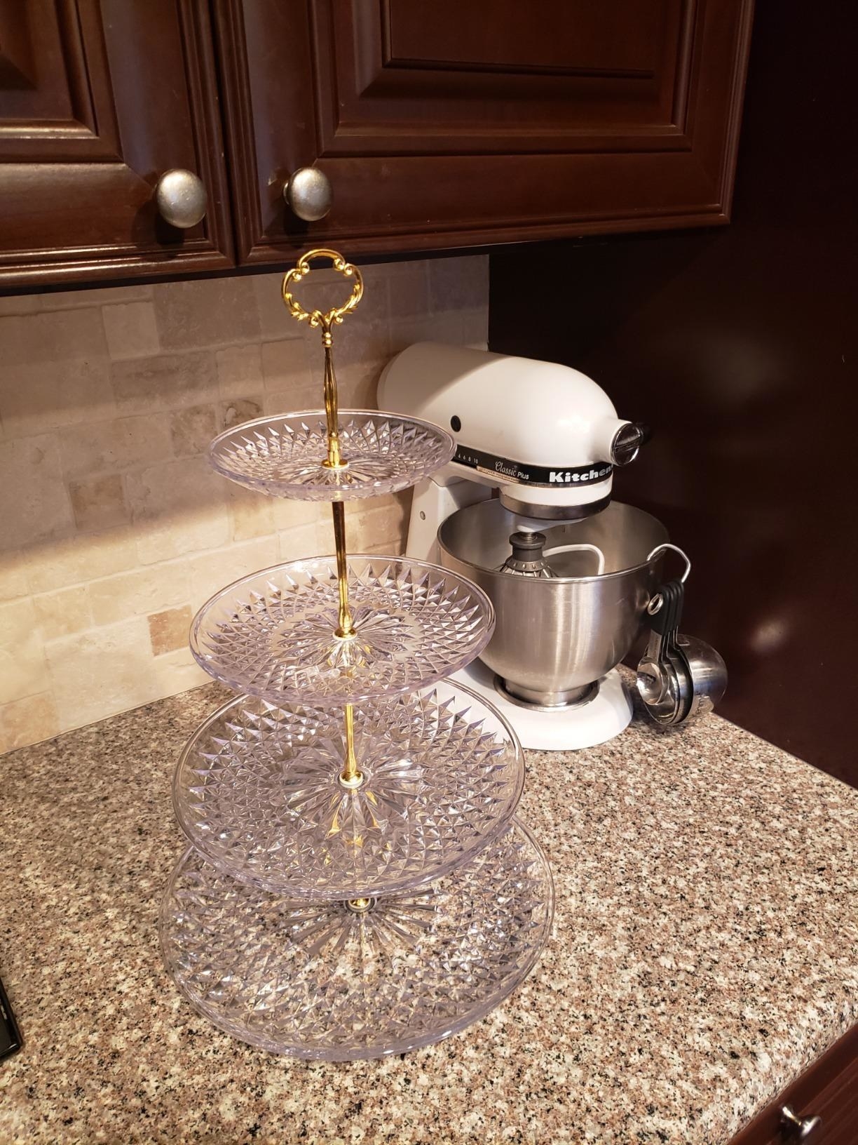 Reviewer image of clear serving four-tier tray with gold accents on kitchen counter