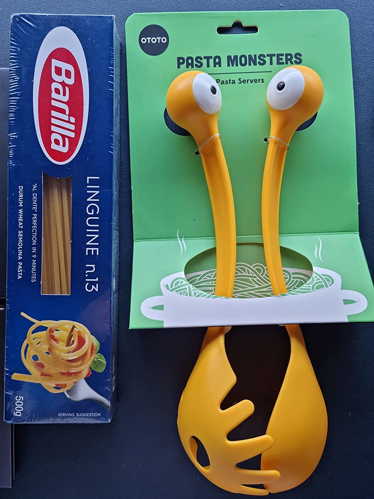 Reviewer image of yellow serving spatulas with monster eyes at the end next to box of pasta