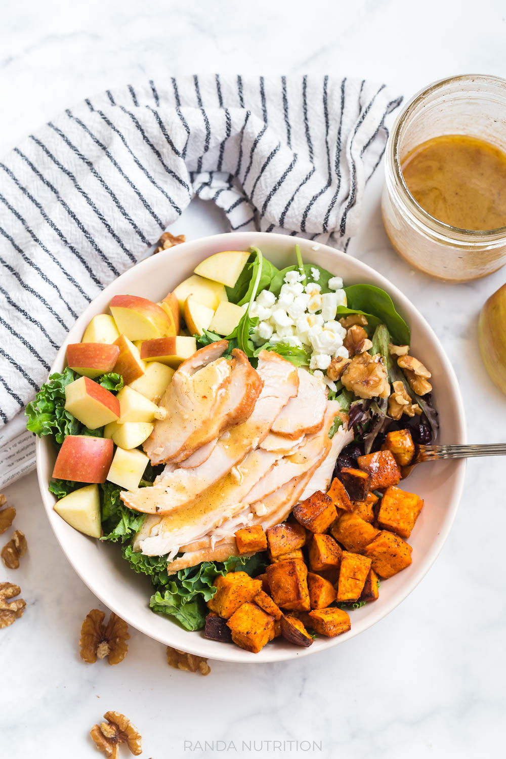 sliced leftover turkey over kale, apples, goat cheese, roasted sweet potatoes for a turkey salad recipe.