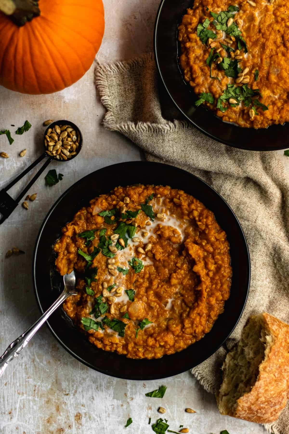 Creamy spiced pumpkin soup with lentils swirled in a bowl.