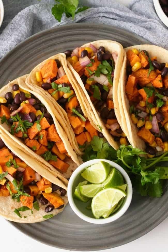 Loaded with tender sweet potatoes, tasty black beans, corn, fresh toppings, and garnished with lime, these tacos make a quick weeknight dinner.
