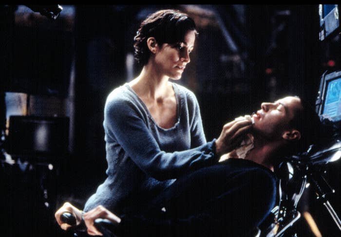 Carrie-Anne Moss as Trinity tending to a sleeping Keanu Reeves as Neo in The Matrix