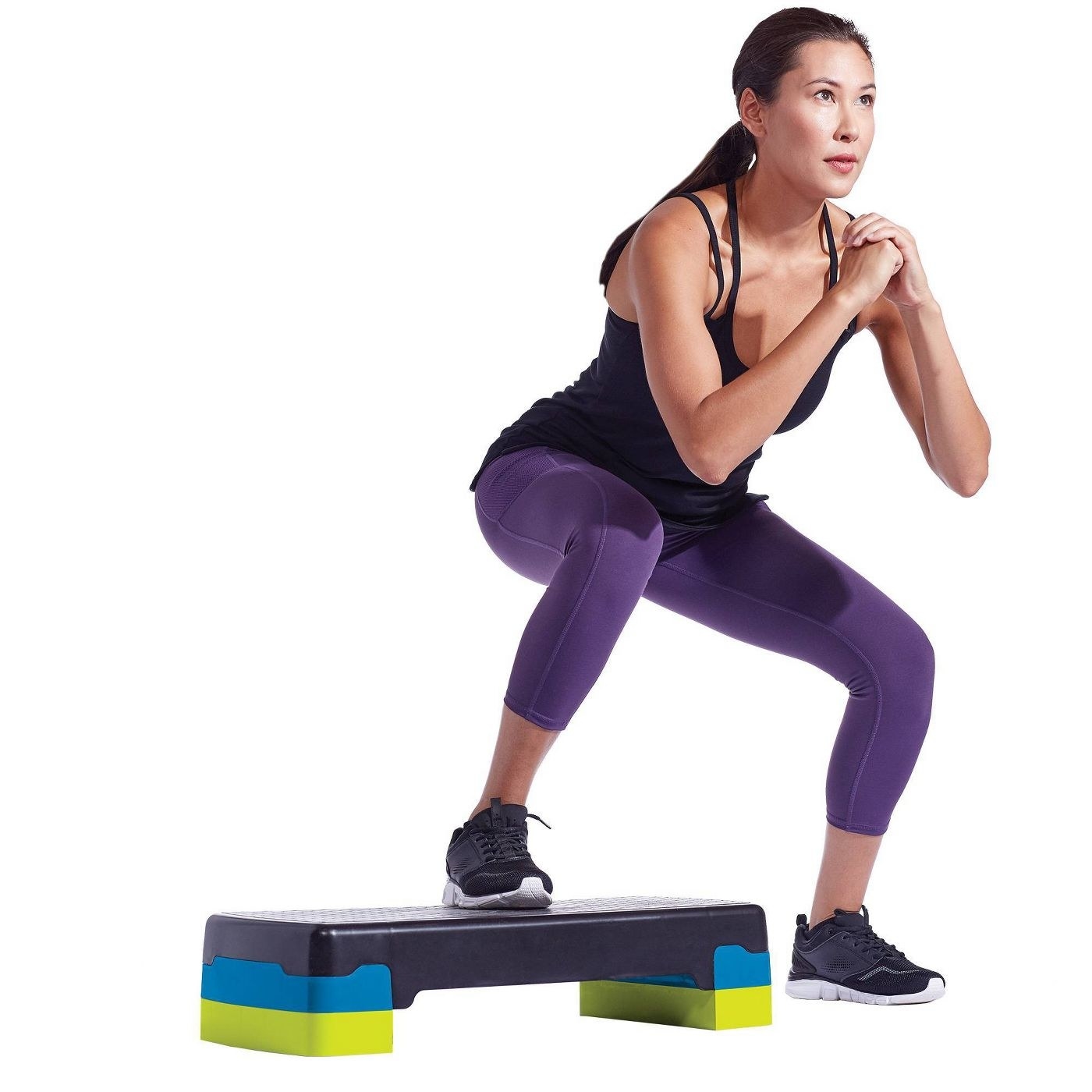 A woman does jump squats on an adjustable step deck