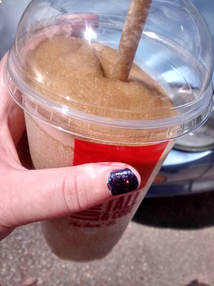 Person holding a large cup of frozen Coke