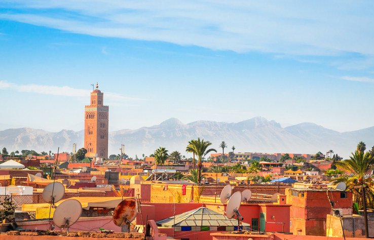 The rooftops of homes in Marrakesh with mountains in the background