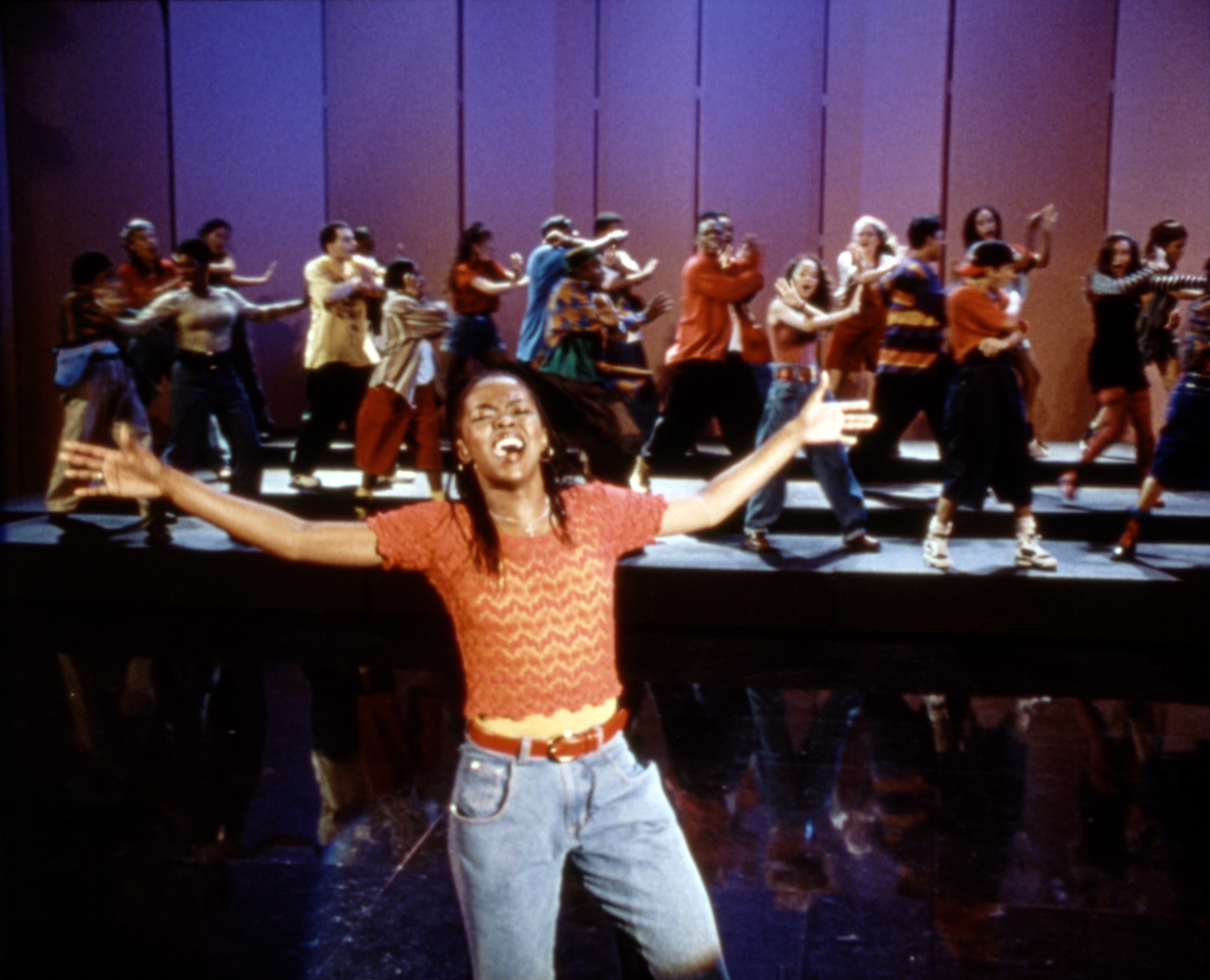 Lauryn hill singing with a group of people behind her