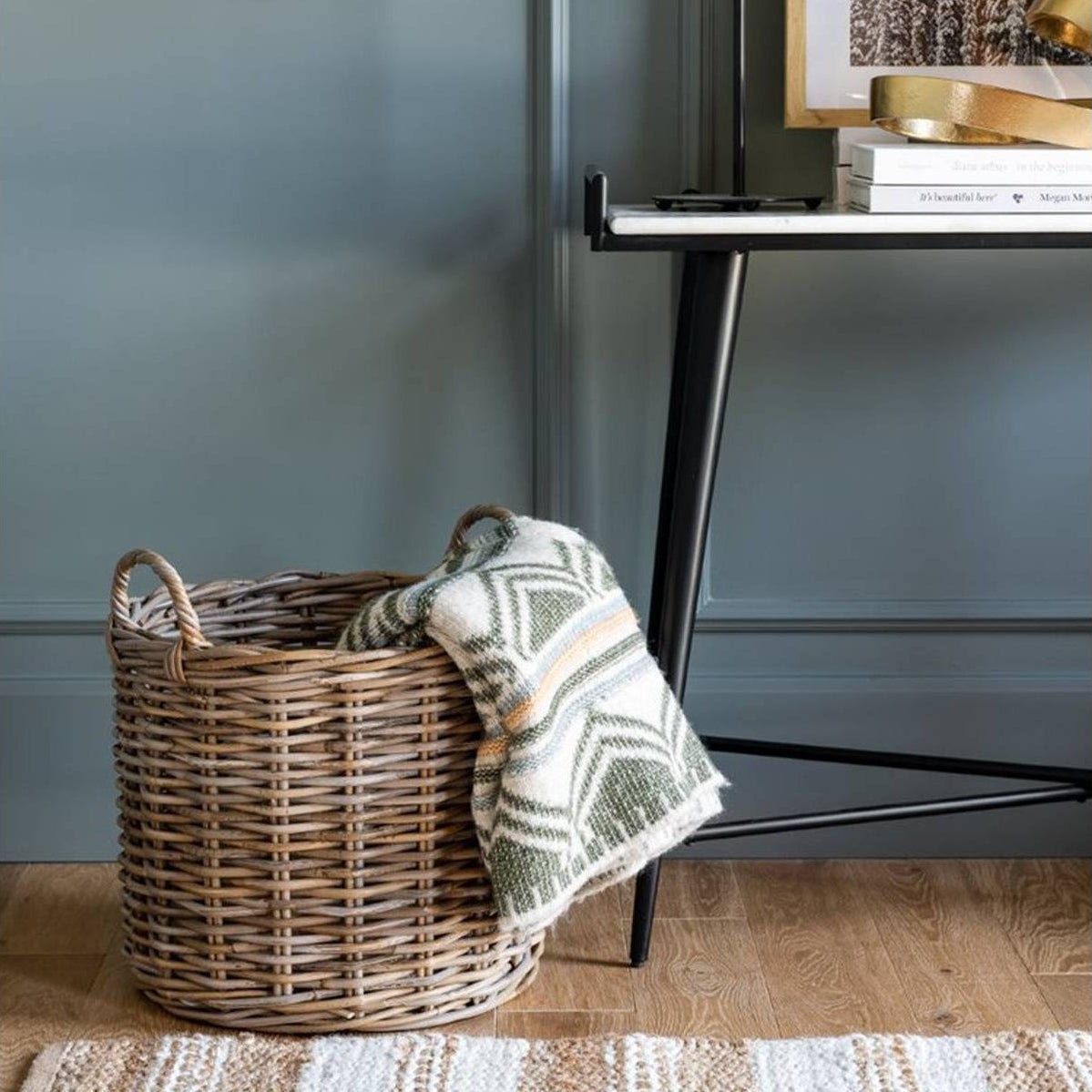 brown/gray round rattan basket on the floor with blanket inside