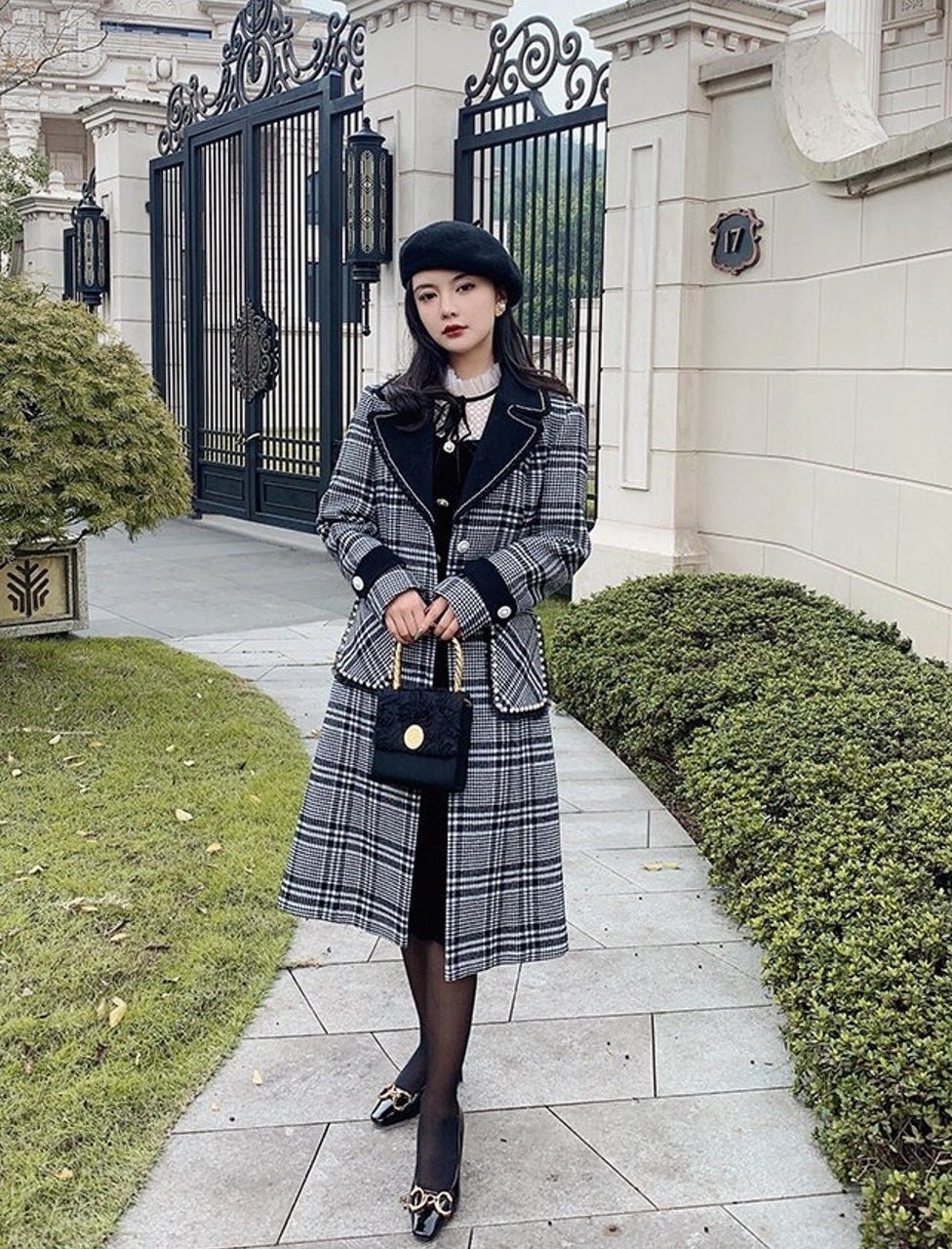 model in black and gray plaid coat with piping on collar and pockets