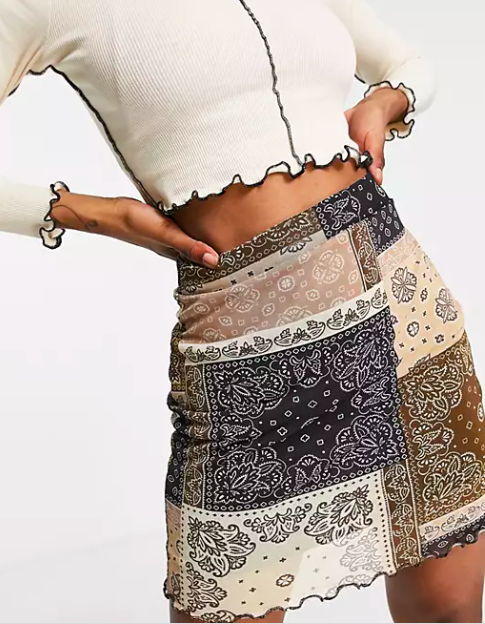 model in super short mixed tan, blush, white, black, and brown bandana print skirt