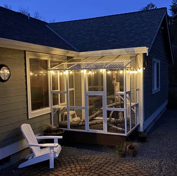 reviewer's cat house placed on a porch and covered in twinkle lights