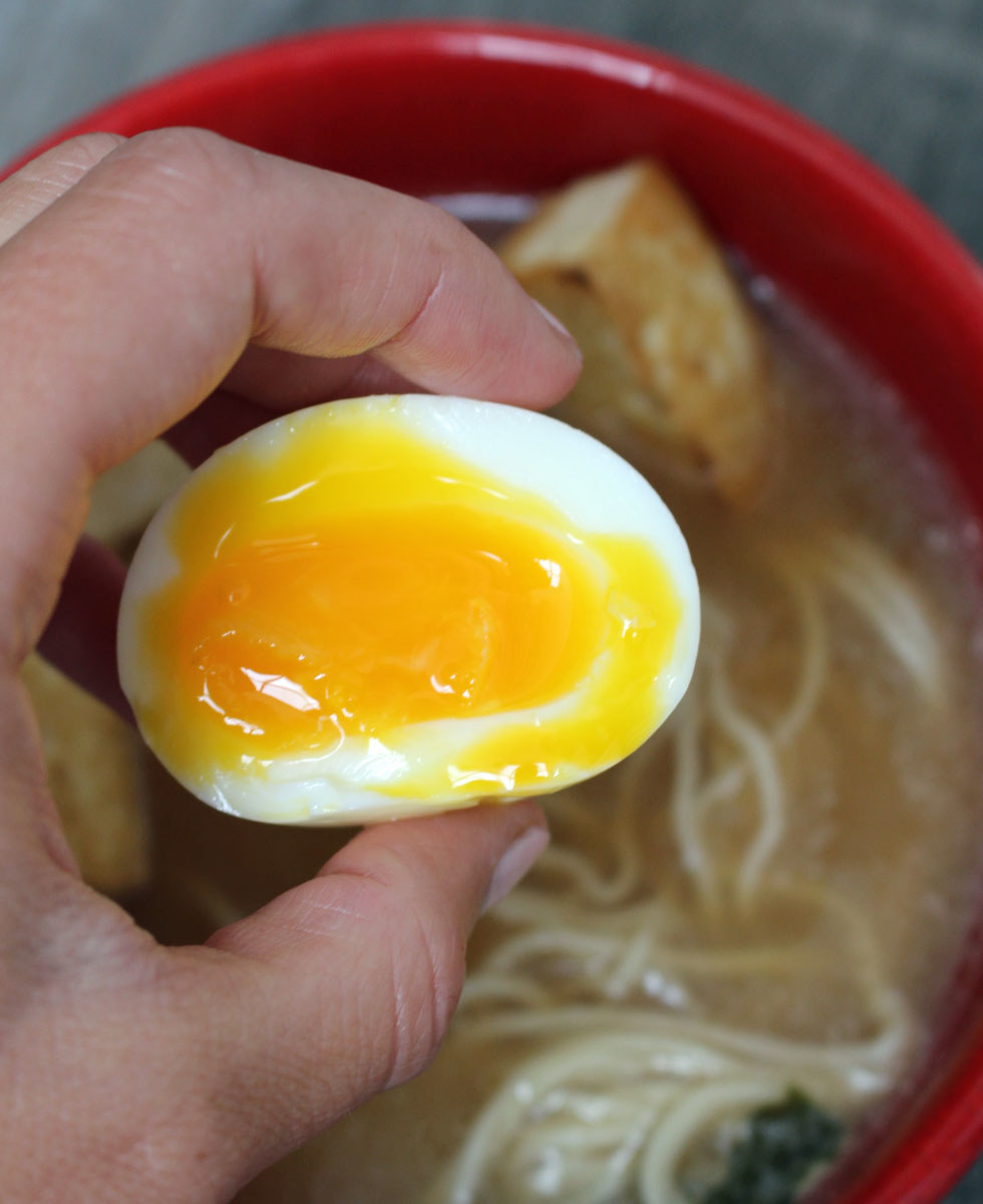 Placing an egg in a bowl of ramen
