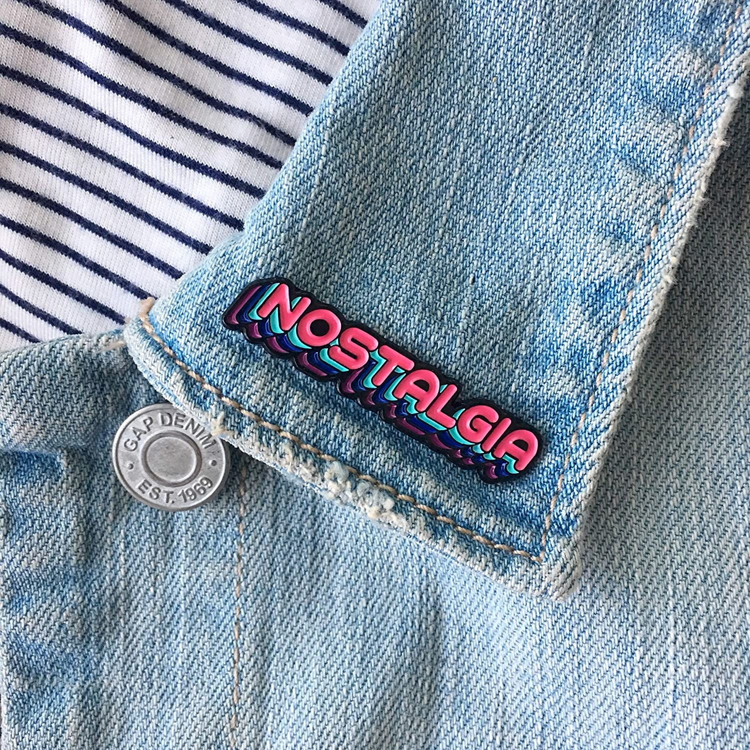 The Nostalgia pin on the lapel of a denim jacket