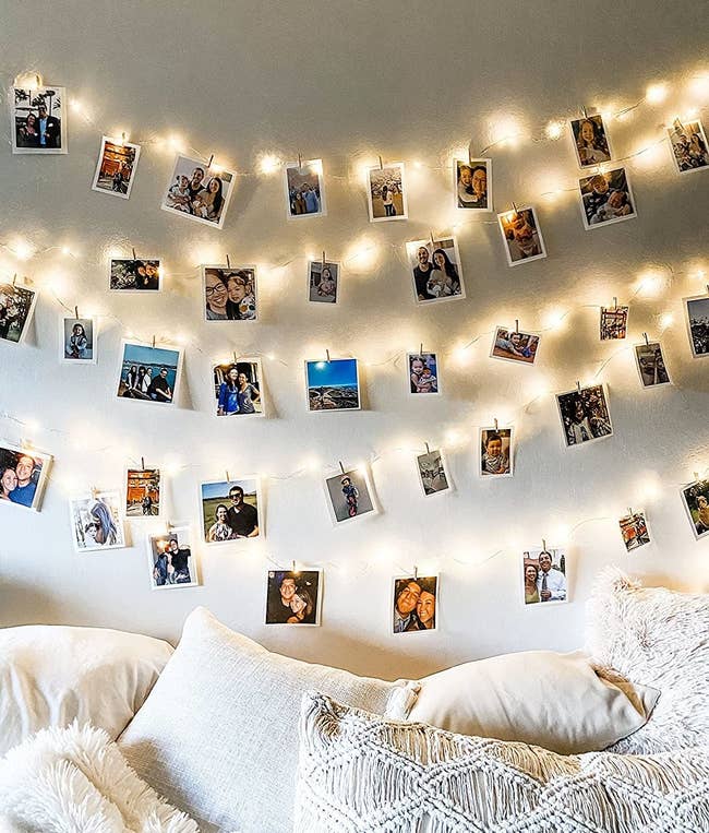 The lights hanging on a wall and strung with photos on clothespins