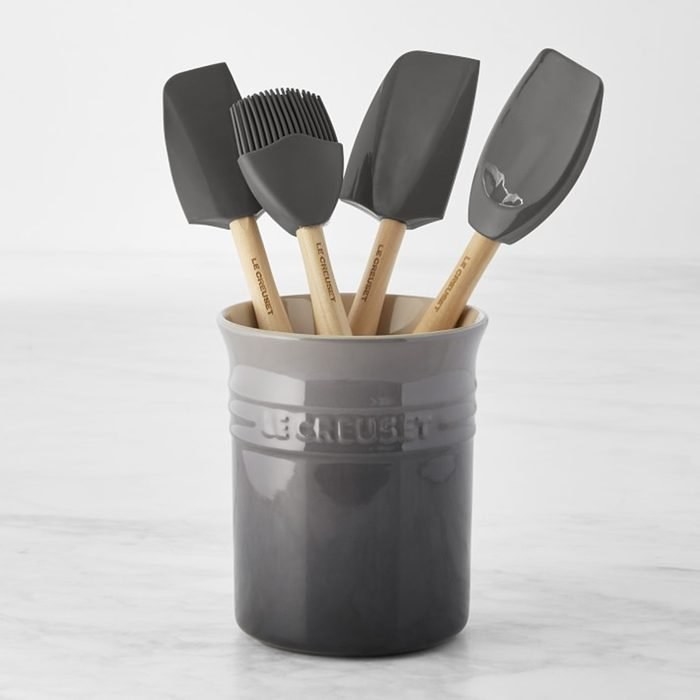 a ceramic le creuset utensil crock with matching utensils inside