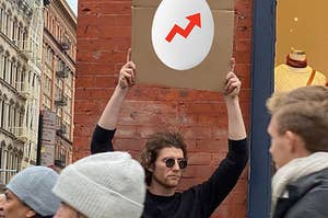 Meme with a guy holding up a sign, on the sign is an egg with the BuzzFeed logo.
