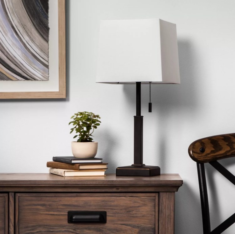 An image of a square stick lamp on top of bedroom furniture