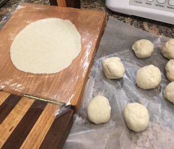 Reviewer photo of a tortilla flattened by the press next to balls of dough
