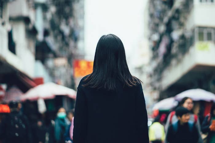 A woman stands alone in a busy city surrounded by people