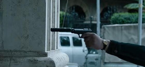 A hitman pointing a gun with a silencer at Maurizio (off-screen) in &quot;House of Gucci&quot;
