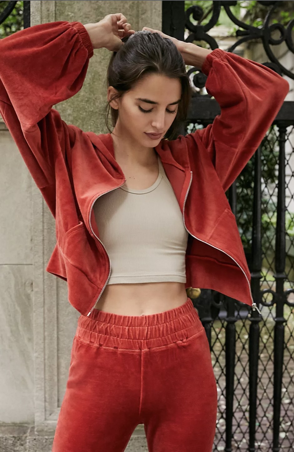 Model wearing the red-orange velour zip-up over a crop top
