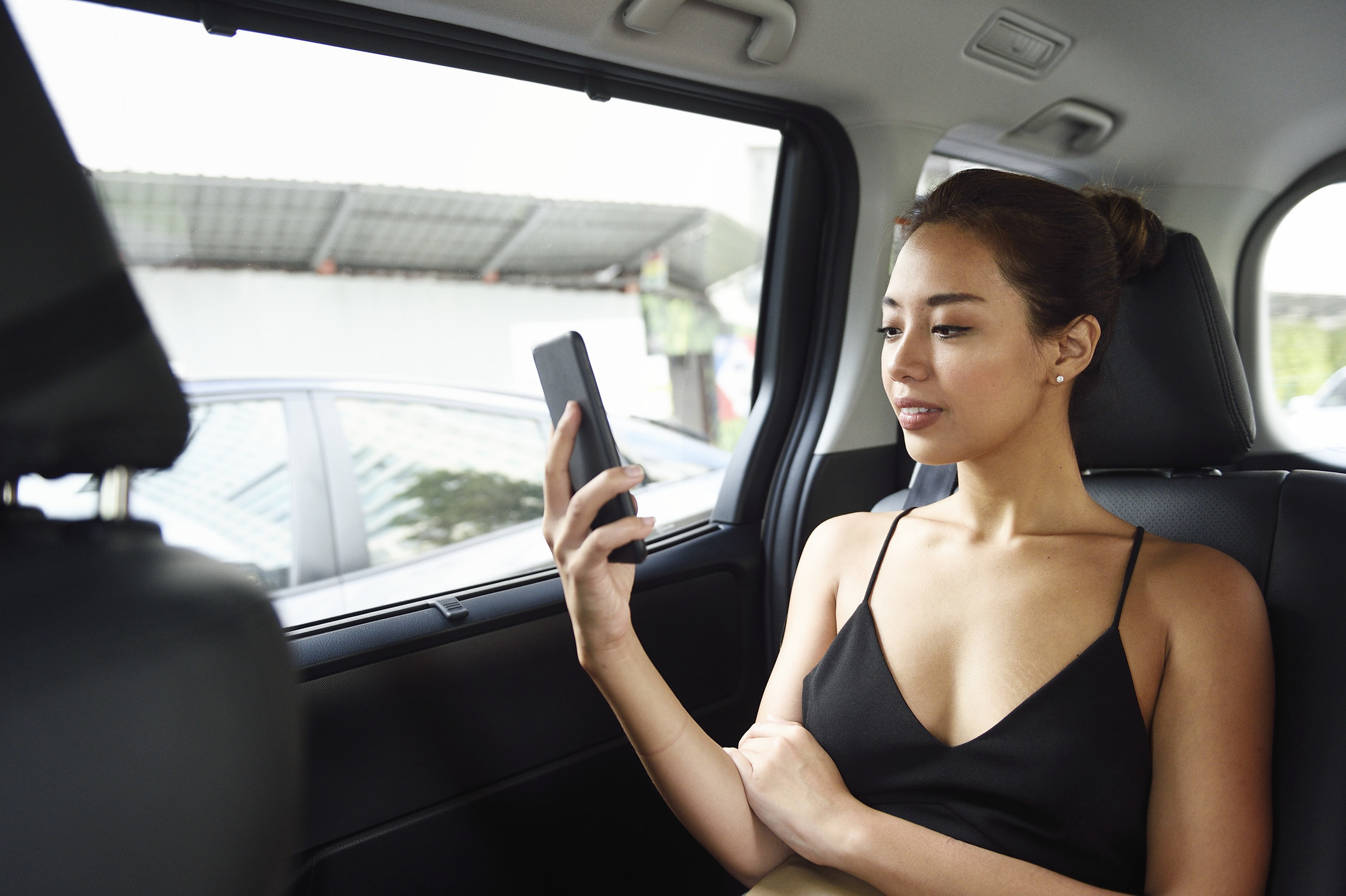 A woman checks her phone while riding in a car