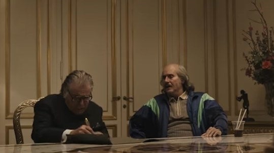 Aldo and Paolo sitting at a table, with the former signing a contract relinquishing his shares of Gucci in &quot;House of Gucci&quot;