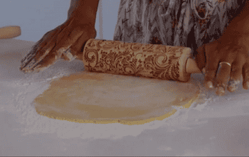 Model using the rolling pin to stamp a design onto cookie dough