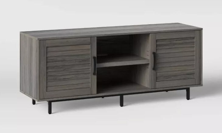 A gray, lightly distressed TV stand with black metal legs and handles. Lots of storage space and 2 doors plus a shelf in the middle creating 2 different levels.