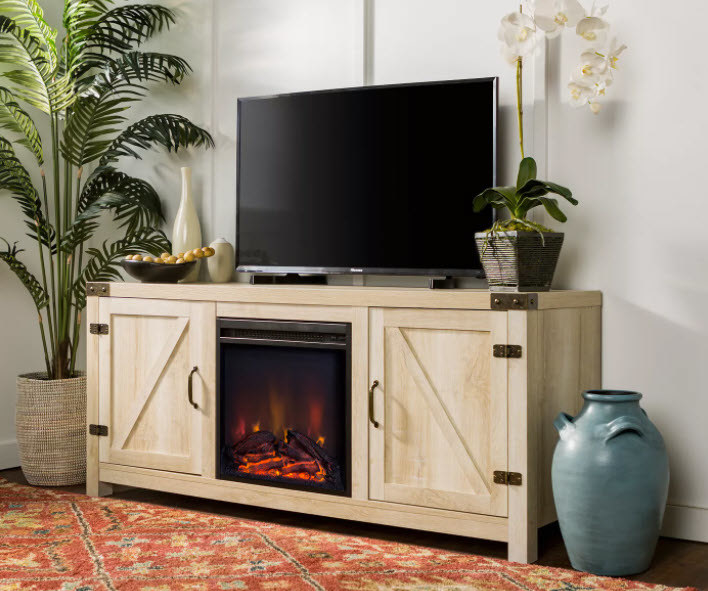 A farmhouse-style TV stand with double-doors and an LED electric fireplace in the middle. Light-brown wooden finish and brown metal accents and handles. TV stand holds up to 65&#x27; TV