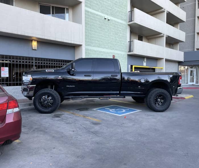A truck parked diagonal in 3 parking spaces, which are also a handicap space, an emergency space, and a delivery space