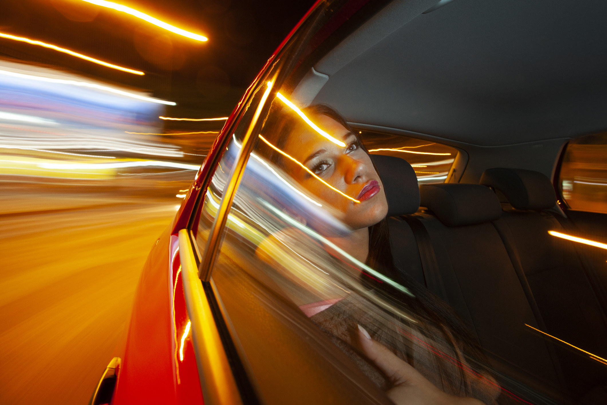 Woman in the backseat of a car in motion at night