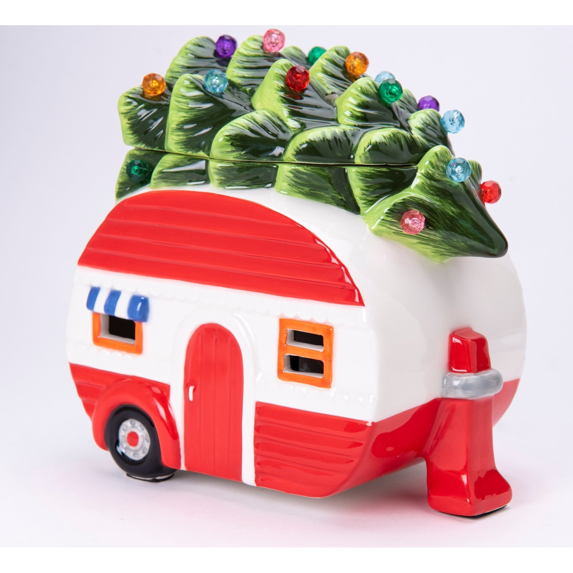 A ceramic wax warmer designed to look like a vintage RV camper with a Christmas tree tied to its roof