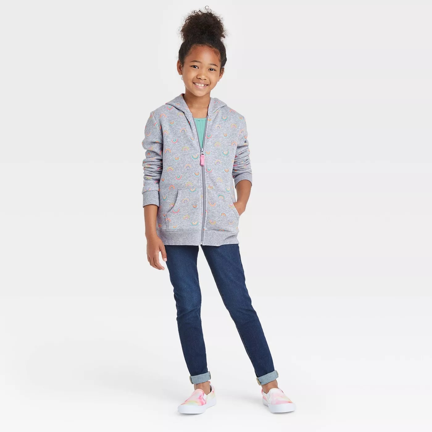 A child wearing a gray zip-up with a rainbow print