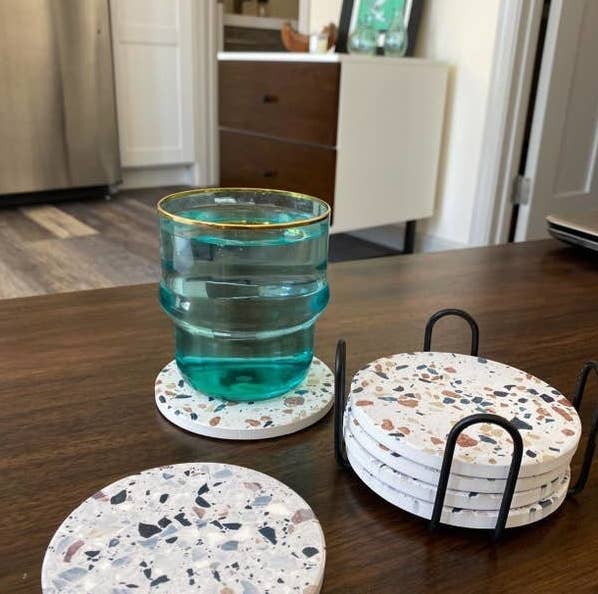 a coffee table topped with four coasters in their stand, one by itself, and one with a blue cup on top