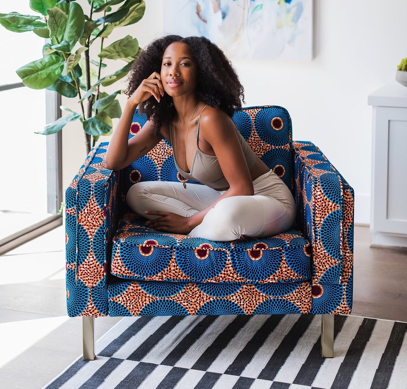 model sitting in a blue and orange African-printed armchair