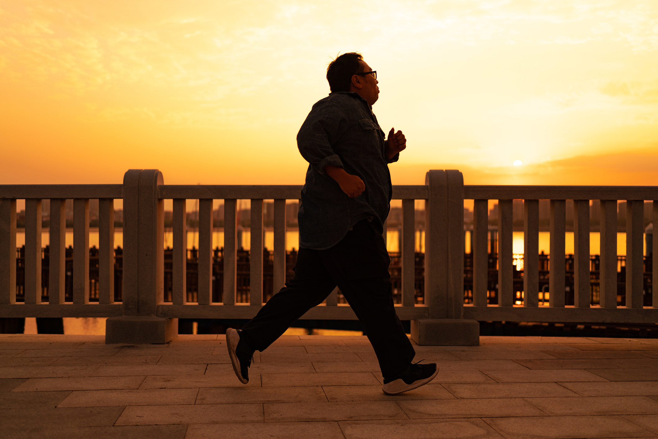 Man runs across a bridge during sunset