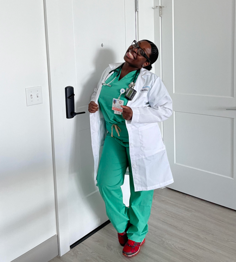 Dr. Savice smiles in her scrubs and white coat