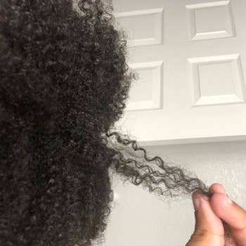 reviewer with 4c hair holding a section of their hair showing how strong and hydrated their strands look