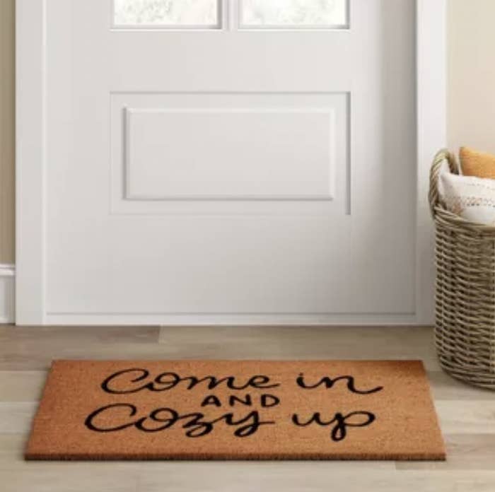 The brown doormat with the message in black cursive font