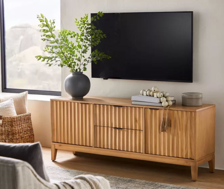 A neutral/light-brown scallop-designed TV stand/media console that has 2 doors that open towards you as well as 2 pull-out drawers in the middle. All wood finishes.
