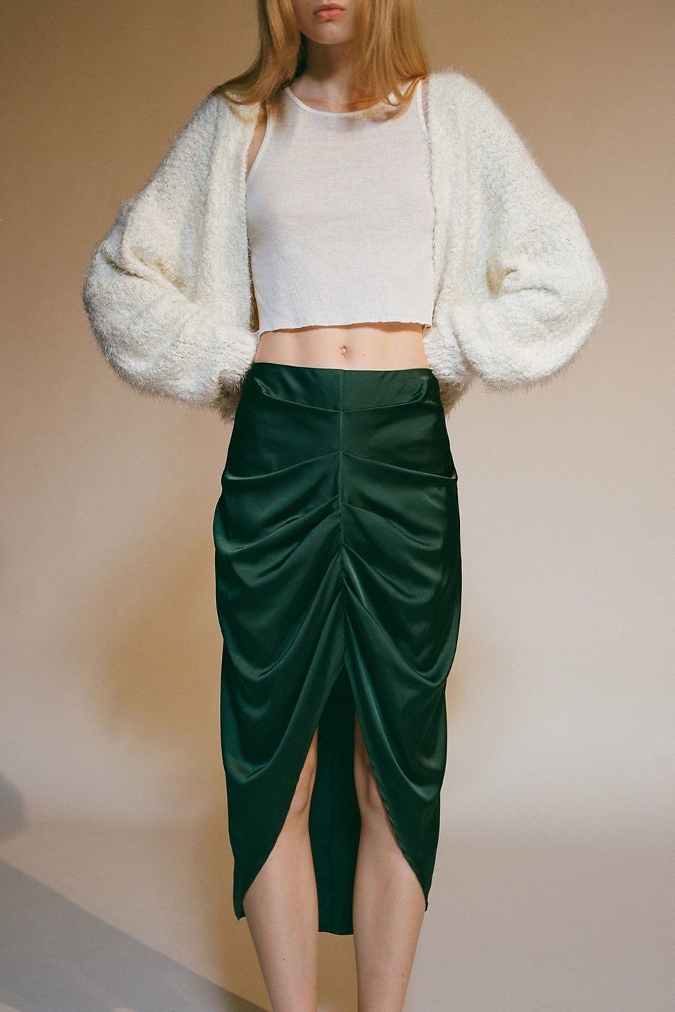 model in an emerald green draped skirt with a ruche up the center